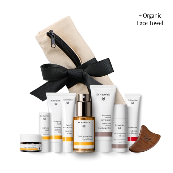 Dr. Hauschka skincare set with black ribbon, toiletry pouch, and organic face towel on a white background.