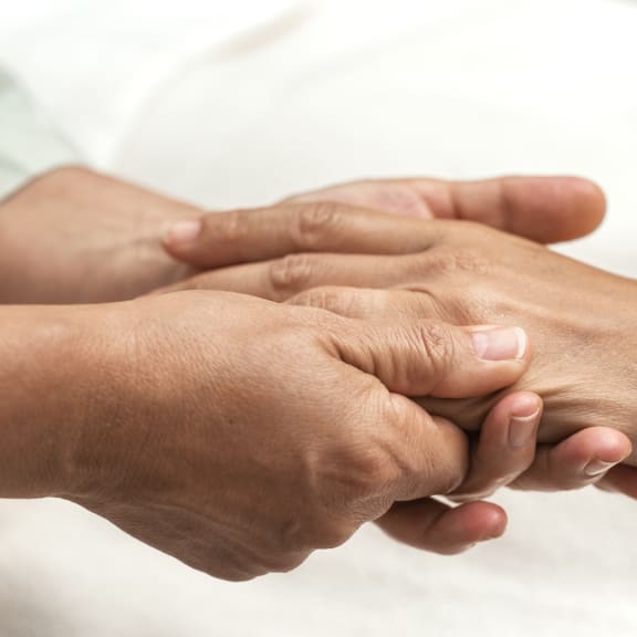 Close-up of two women holding hands in a supportive gesture.