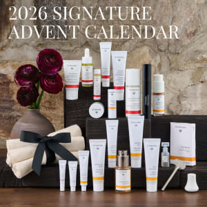 Dr. Hauschka 2026 Signature Advent Calendar display with skincare products, flowers and a gift box on dark wooden steps.