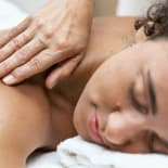 Close-up of a woman getting a shoulder massage while resting her face on a towel.