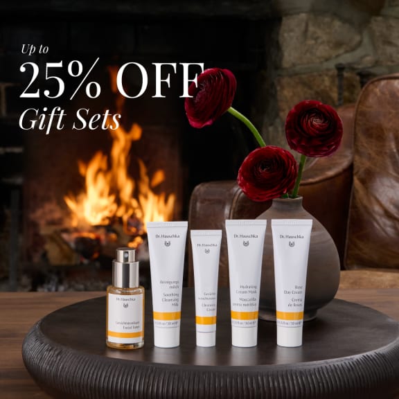 Promotional image for Dr. Hauschka gift sets, showing 25% off skincare products on a table by a fireplace.
