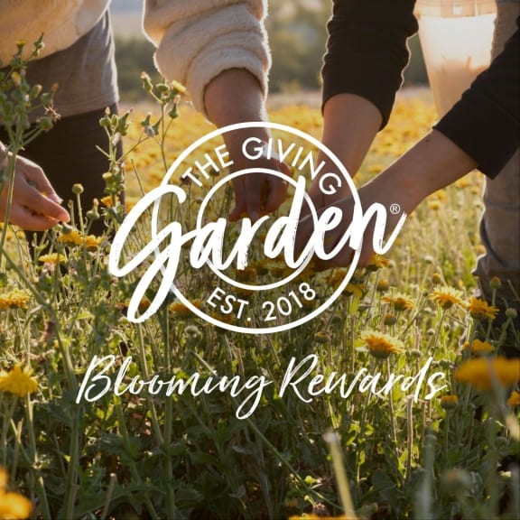 People picking flowers in a sunlit field with overlaid text, 'The Giving Garden' and 'Blooming Rewards'.
