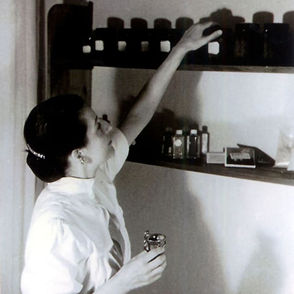 Elizabeth Sigmund reaching for a bottle on a shelf.