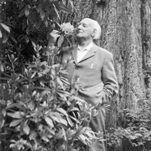 Dr. Rudolf Hauschka smelling a flower outdoors.