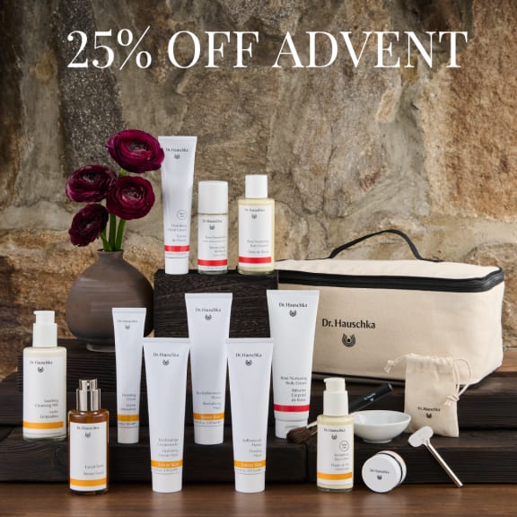 25% off Advent promotion with Dr. Hauschka skincare gift set, pouch, vase of dark flowers, and product bottles.