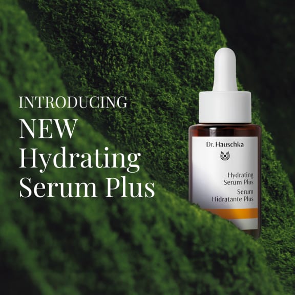 Dr. Hauschka Hydrating Serum Plus bottle on mossy green background with launch text.