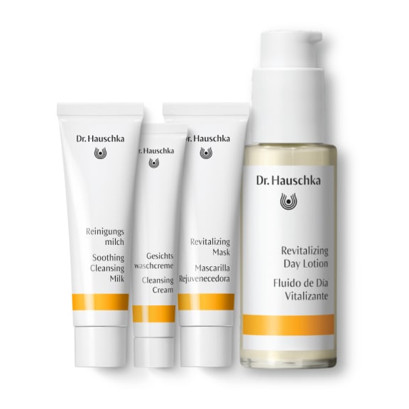 Four Dr. Hauschka skincare products on a white background: three tubes and one pump bottle, all with orange bands., skincare, lotion, day cream, mask, cream