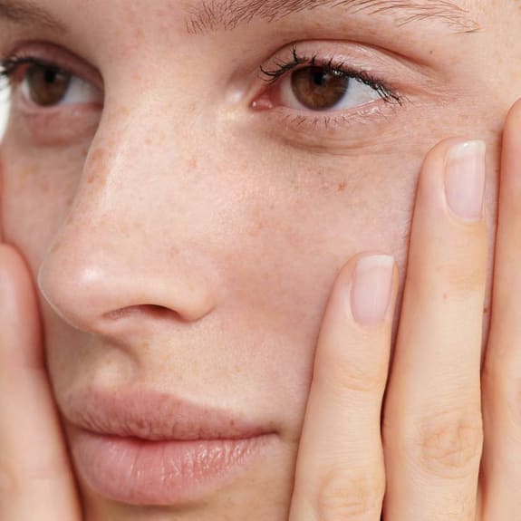 Close-up of a woman's face with hands gently framing her cheeks.